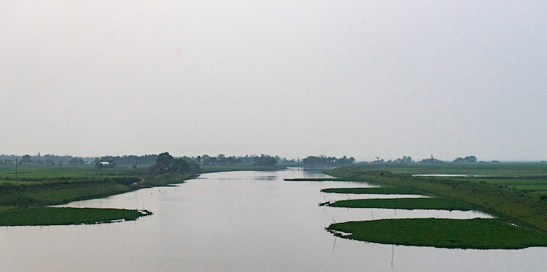 Photo of a river flooding into fields in Bangladesh's northeastern region