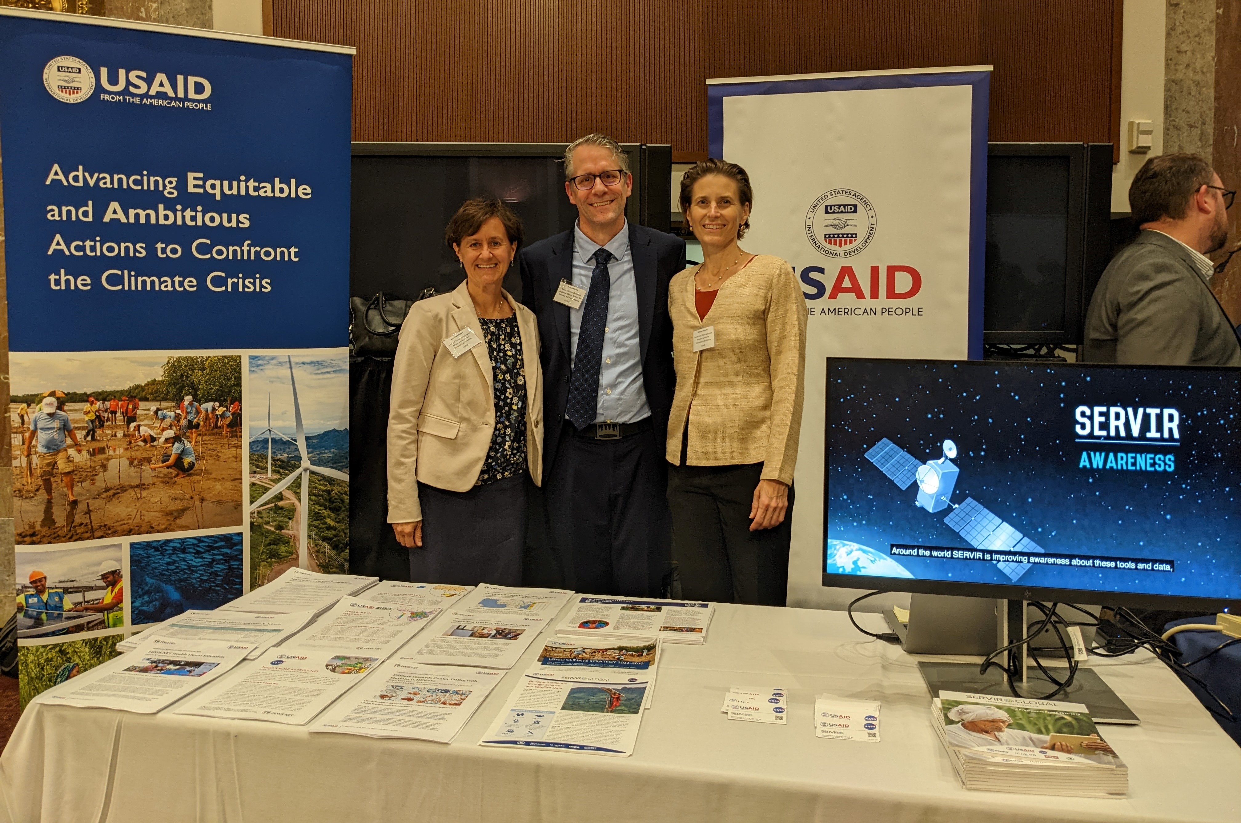 3 USAID staff standing at table