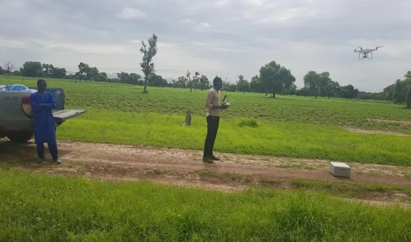 A man flies a drone to collect field data in Senegal.