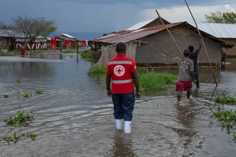 International Red Cross Red Crescent worker wades through flooding
