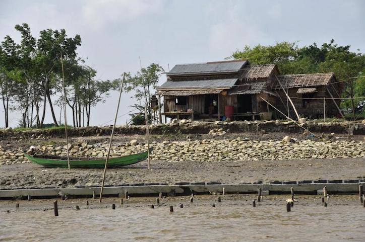 Photo of house and fishing boat along Myanmar riverbank