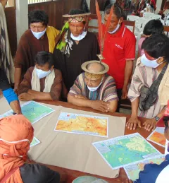 Indigenous community members evaluate maps while sitting at a table in Peru in June 2022
