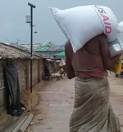 A man in southeast Asia carrying grain from USAID