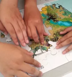 hands putting together a puzzle of southeast asia with logos of SERVIR and NASA