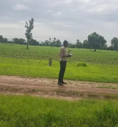 A man flies a drone to collect field data in Senegal.