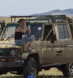 woman with binoculars sitting on a truck on safari in East Africa