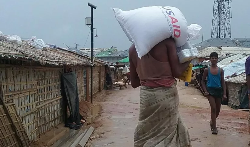 A man in southeast Asia carrying grain from USAID
