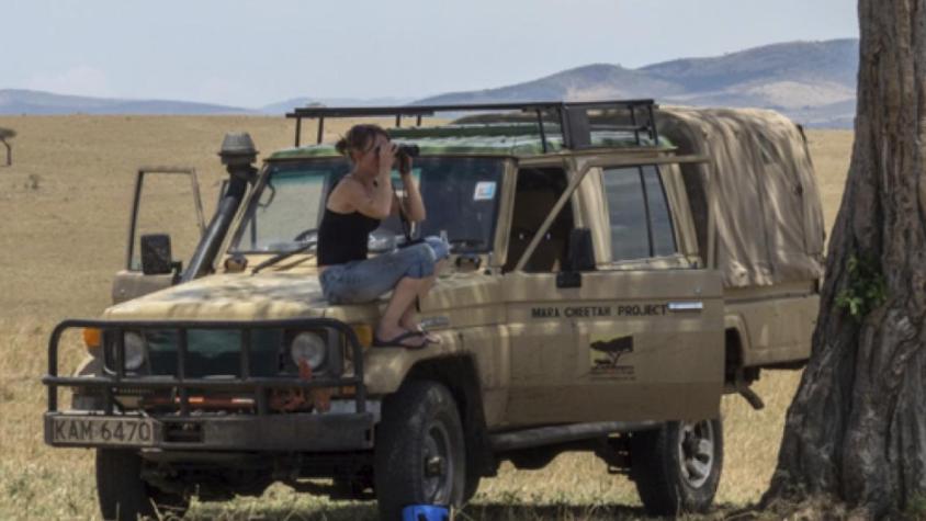 woman with binoculars sitting on a truck on safari in East Africa
